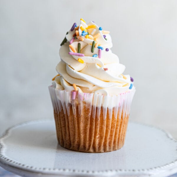 A vanilla cupcake piped with swiss meringue buttercream and colorful sprinkles.