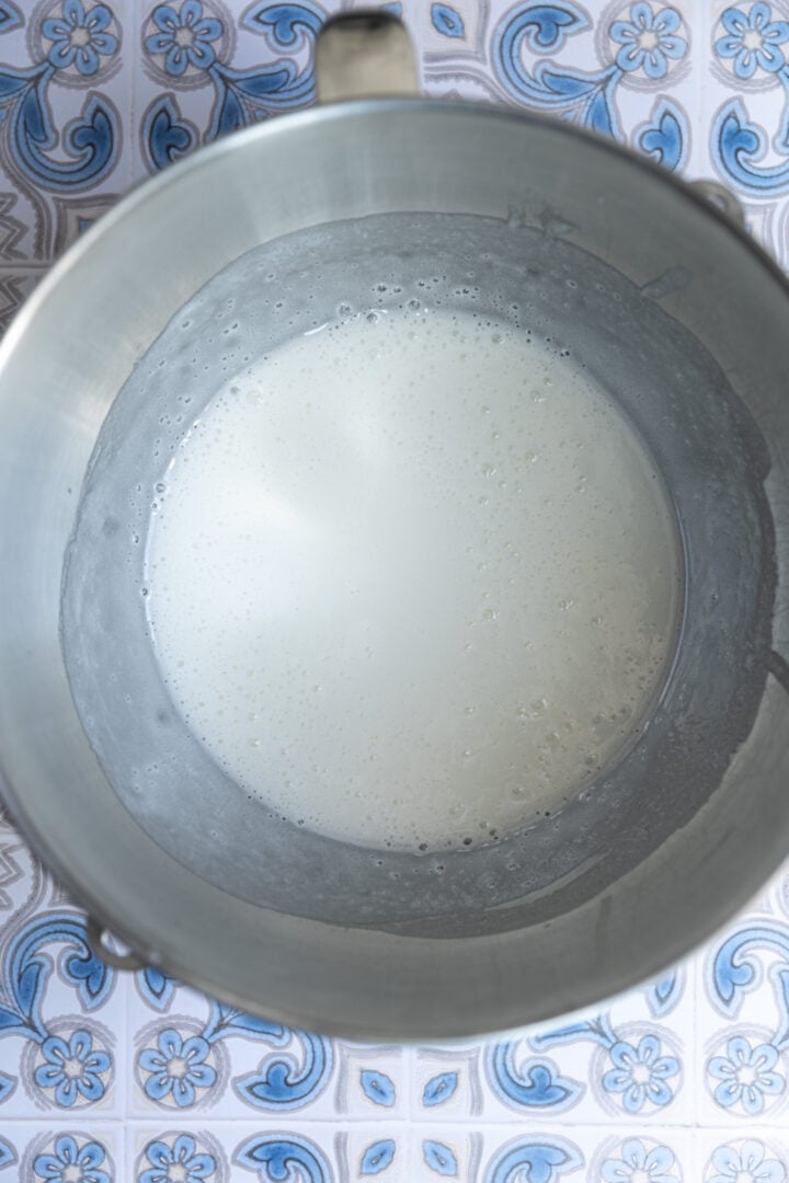 Egg whites, sugar, and corn starch whisked into a thin foam in a bowl.