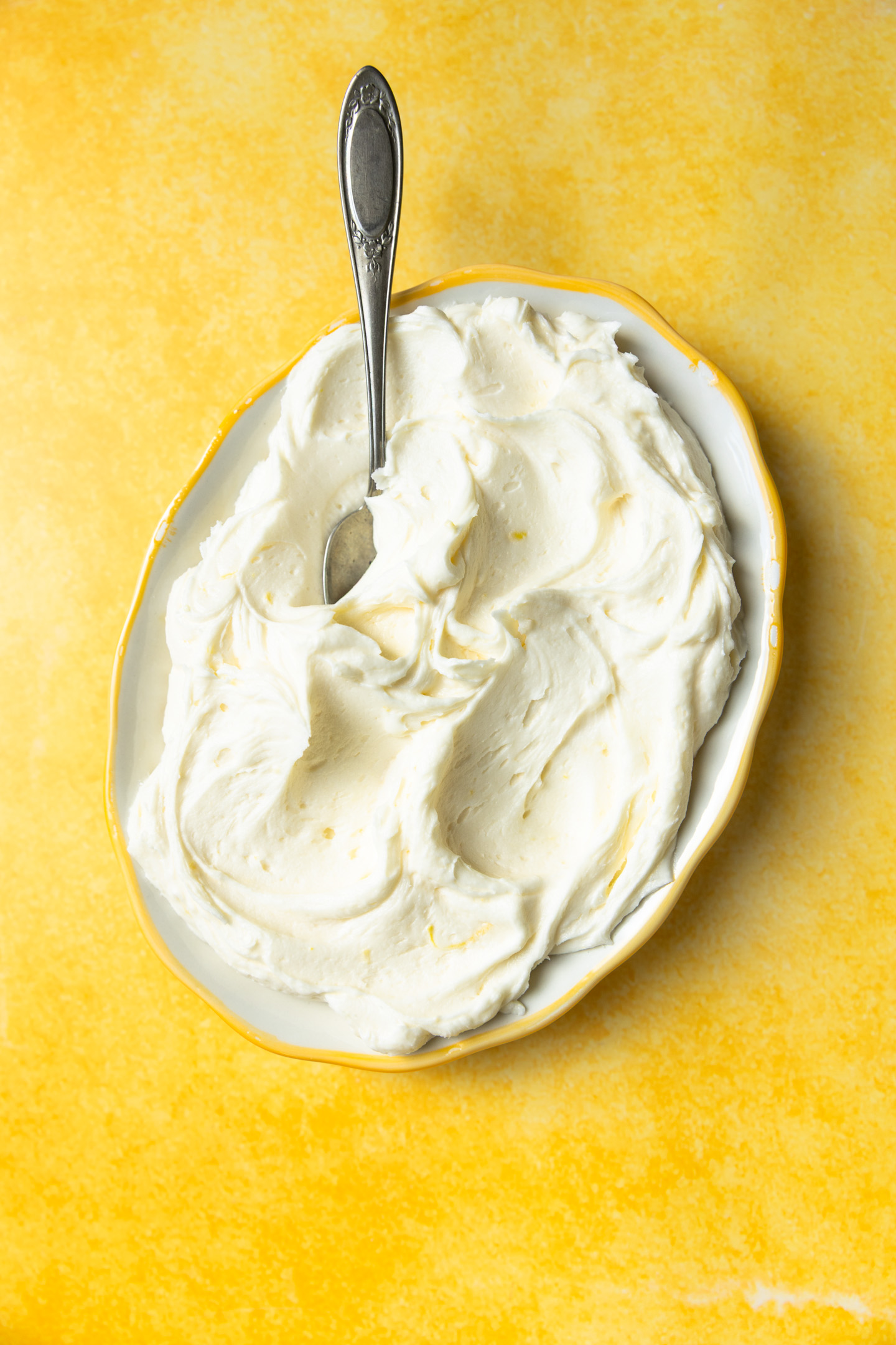 Lemon curd frosting on a platter with a spoon