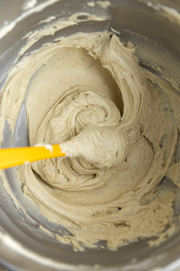 Pistachio icing in a mixing bowl with a spatula.