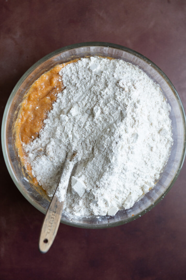 Dry ingredients on top of wet ingredients in a large glass bowl.
