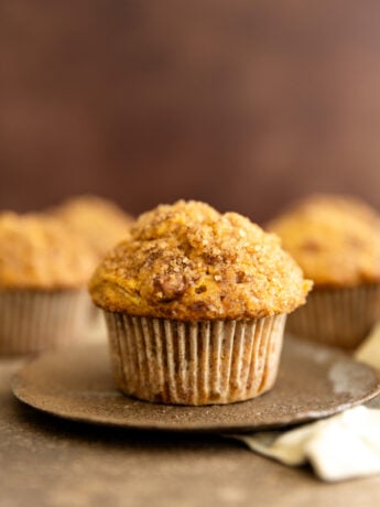 A pumpkin muffin on a brown plate.