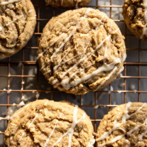 Apple cookies with a white drizzle on a wire rack.