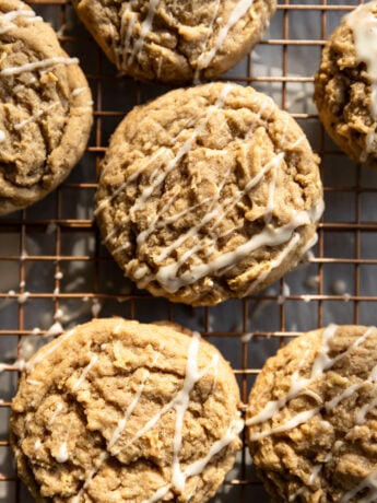 Apple cookies with a white drizzle on a wire rack.