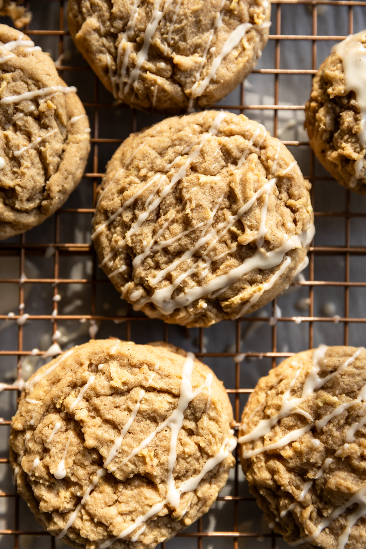 Apple cookies with a white drizzle on a wire rack.