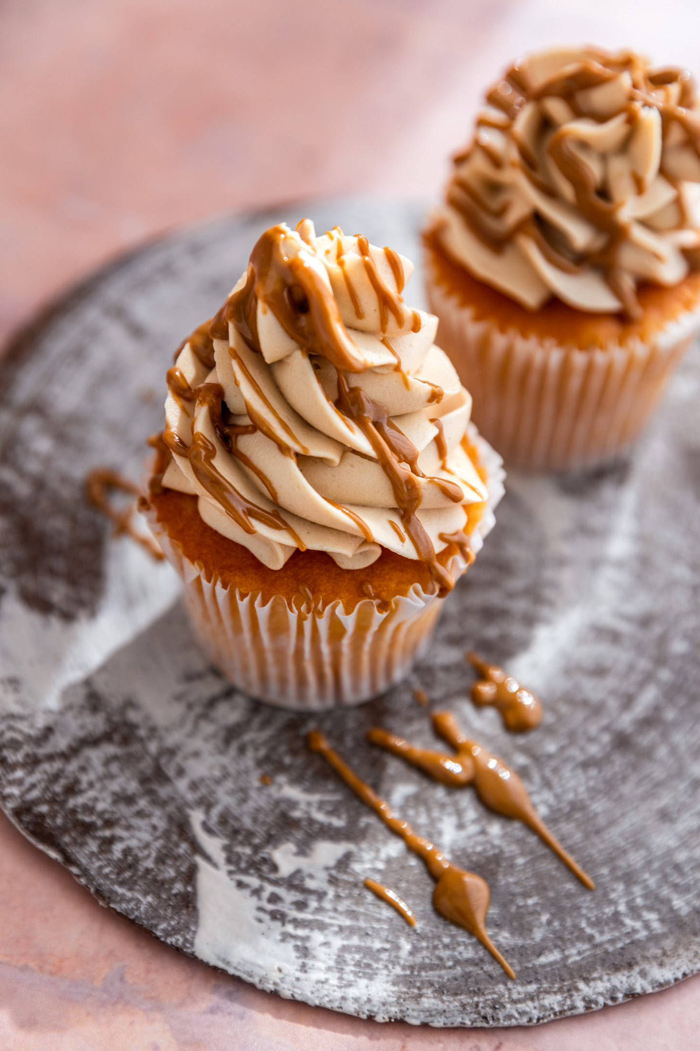 A cookie butter cupcake drizzled with cookie butter icing on a brown plate.