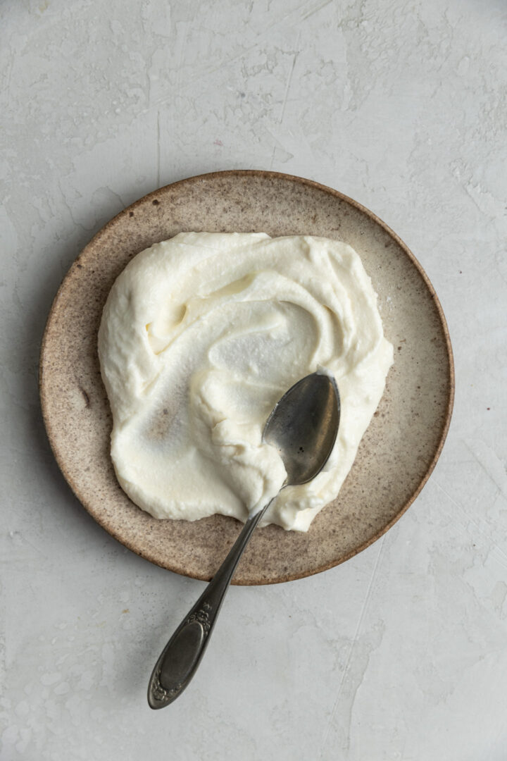 Cream cheese frosting without powdered sugar spread on a plate.