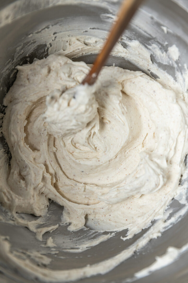 Browned butter frosting in a mixing bowl with a spatula. 