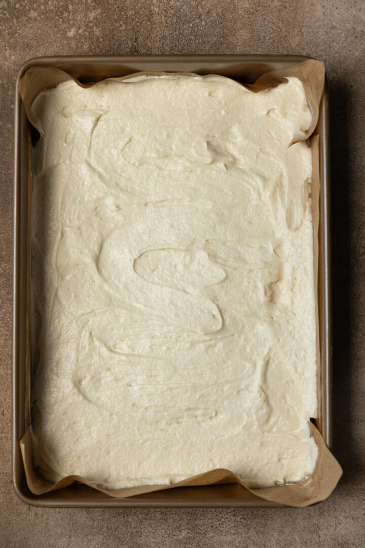 Butter cake batter spread evenly in a 9x13 pan.