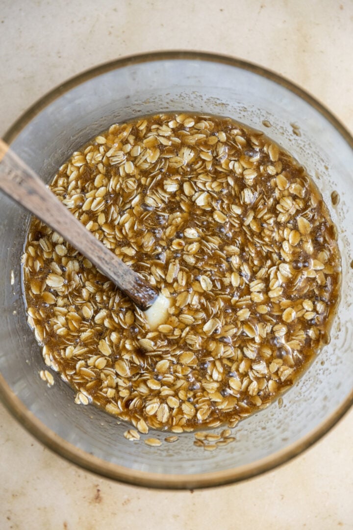 Wet ingredients and oatmeal added to a glass bowl.
