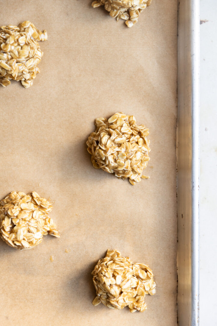 Oatmeal cookie dough balls on a baking sheet lined with parchment paper.