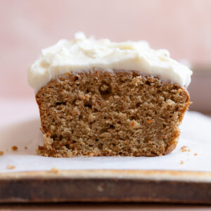 A carrot cake loaf standing on parchment covered cutting board.
