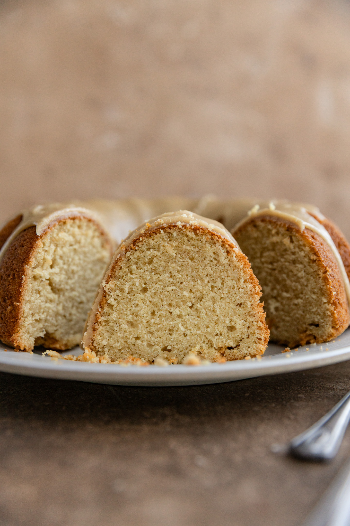 A slice of a brown sugar bundt cake standing up on a plate.