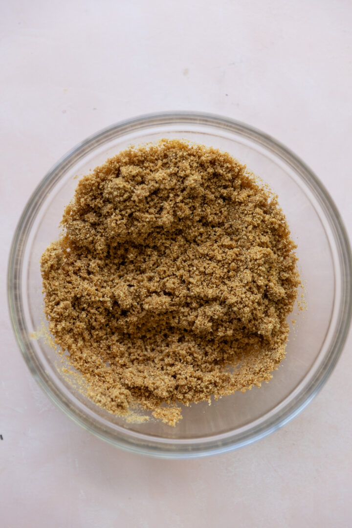 Graham cracker crumbs and melted butter in a glass bowl.