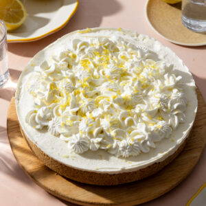 A no bake lemon cheesecake decorated with whipped cream and fresh lemon zest.