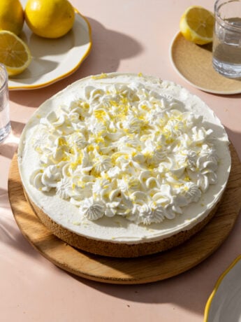 A no bake lemon cheesecake decorated with whipped cream and fresh lemon zest.