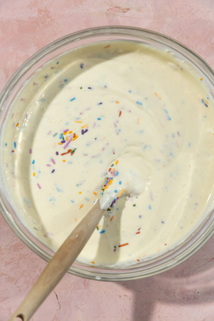 Cheesecake batter with sprinkles in a glass bowl.