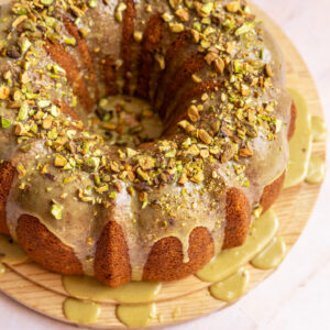 A pistachio bundt cake on a wooden cake plate.