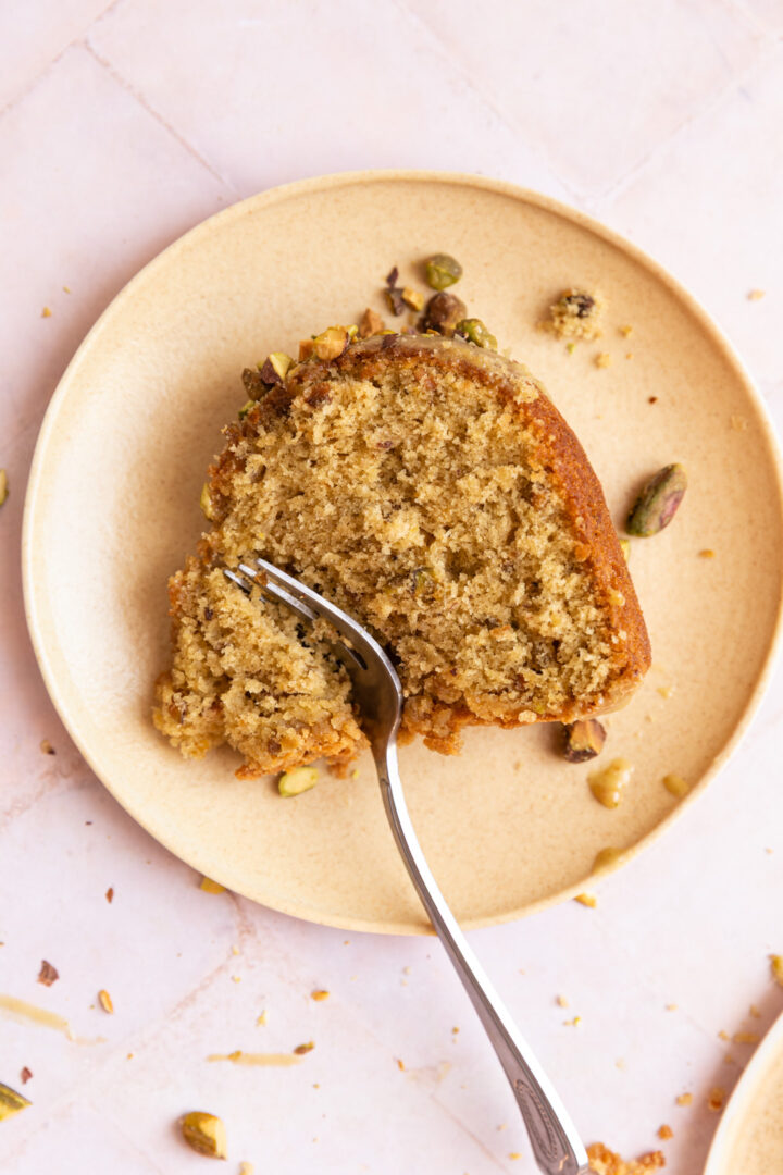 A slice of pistachio bundt cake on a plate with a fork.
