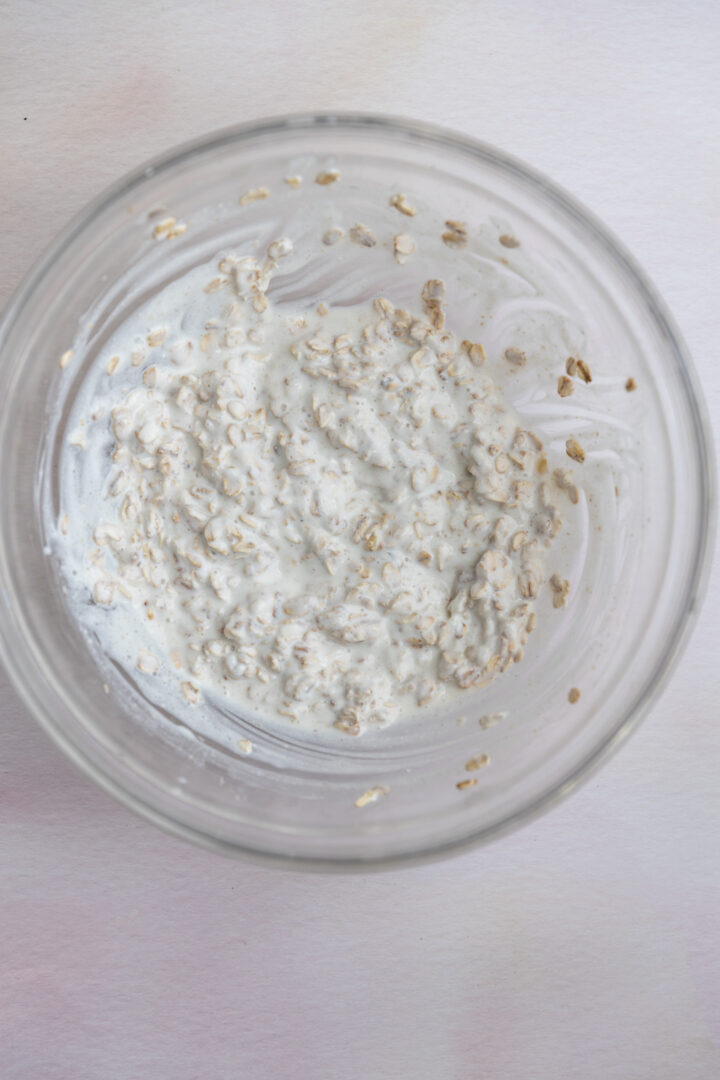 Oats soaking with milk in a glass bowl.