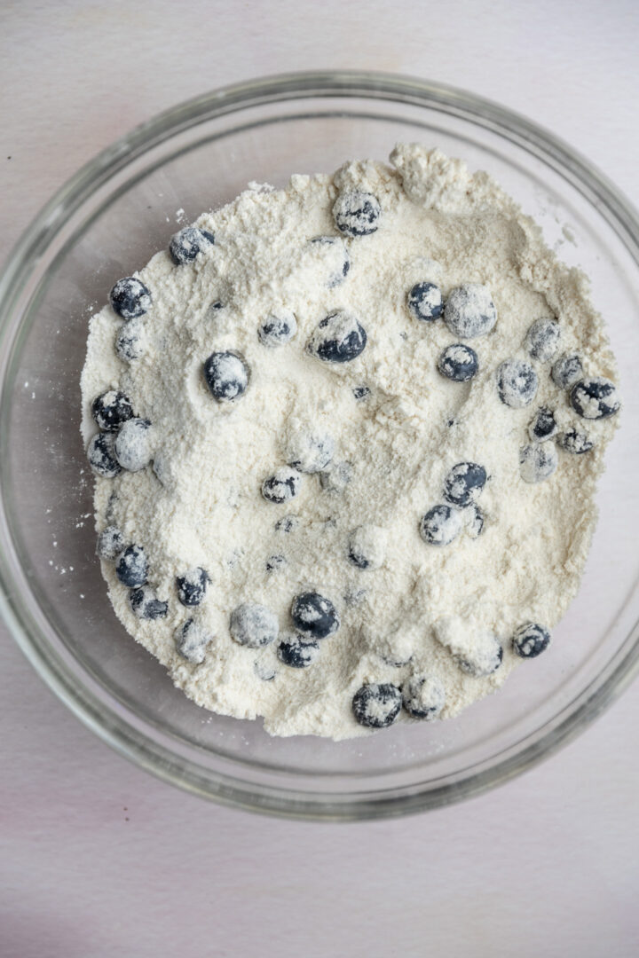 Blueberries tossed in flour in a glass bowl.