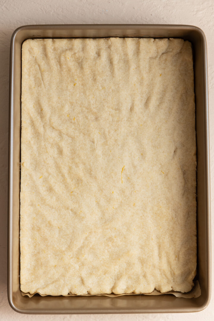 Lemon shortbread pressed into a pan.