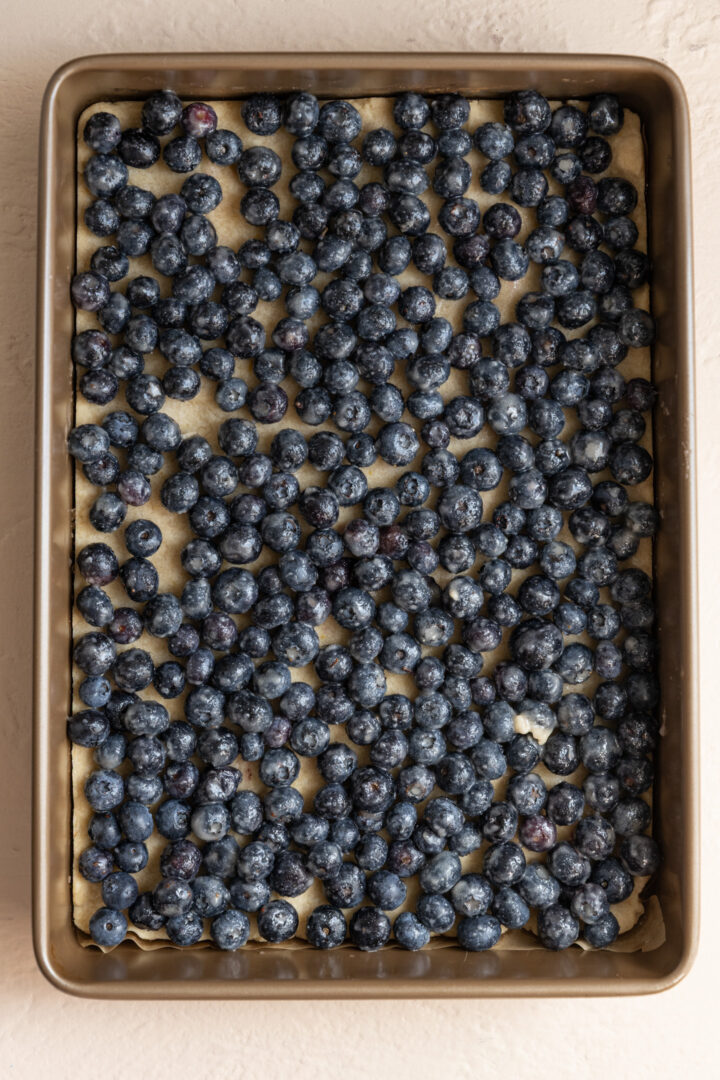 Blueberries on top of lemon shortbread in a pan.