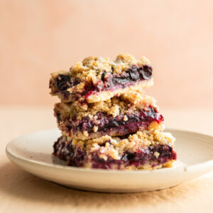 Blueberry lemon crumb bars stacked on top of each other on a white plate.