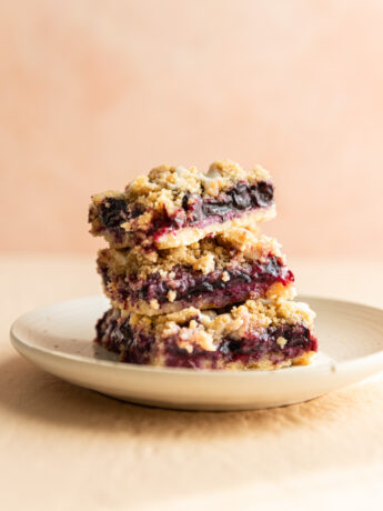 Blueberry lemon crumb bars stacked on top of each other on a white plate.