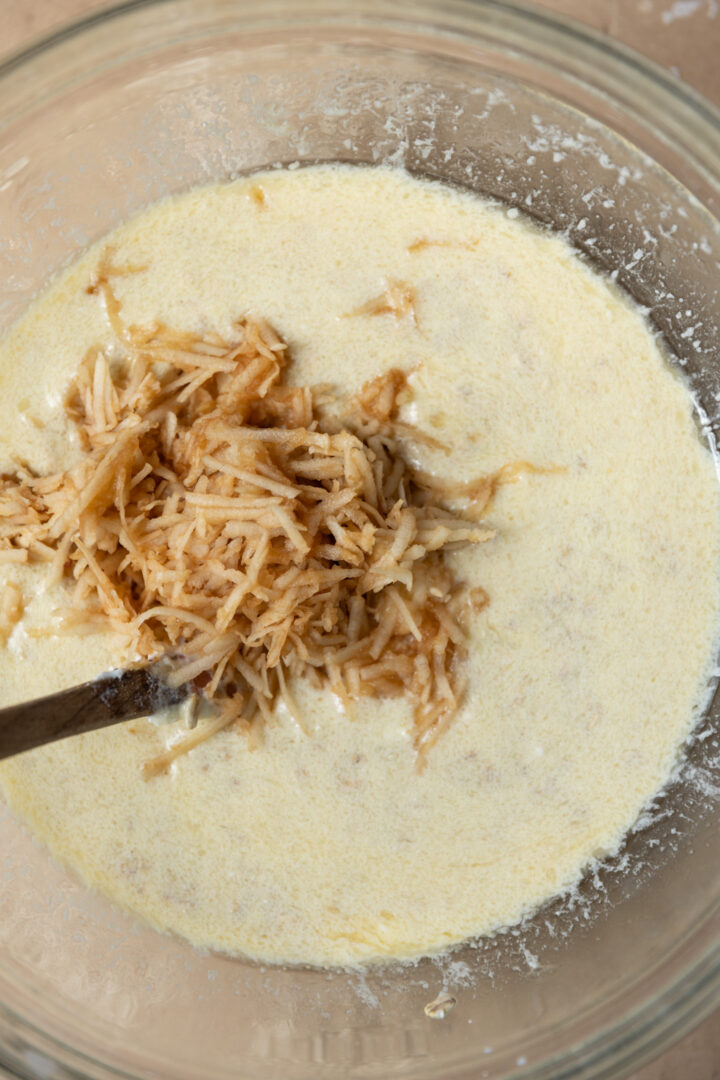Grated apple added to wet ingredients for muffin batter.