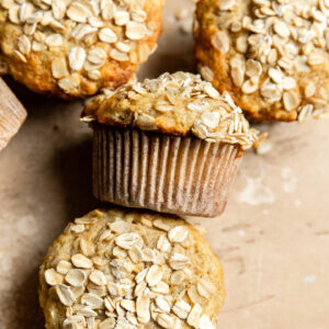 Apple oat muffins on a beige surface.