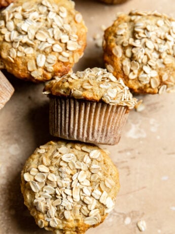 Apple oat muffins on a beige surface.