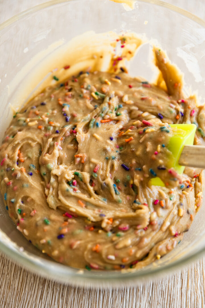 Sugar cookie dough with sprinkles in a glass bowl.
