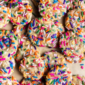 Mini sprinkle drop sugar cookies on a baking sheet lined with parchment paper.