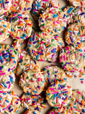 Mini sprinkle drop sugar cookies on a baking sheet lined with parchment paper.