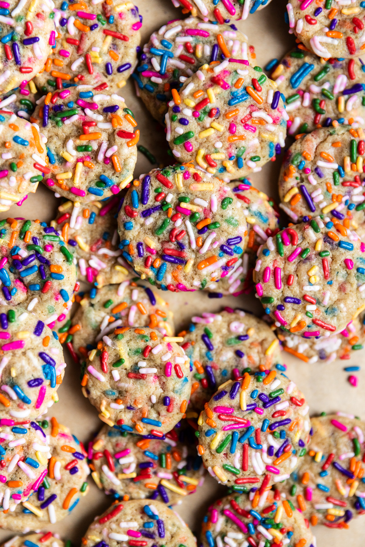 Mini sprinkle drop sugar cookies on a baking sheet lined with parchment paper.