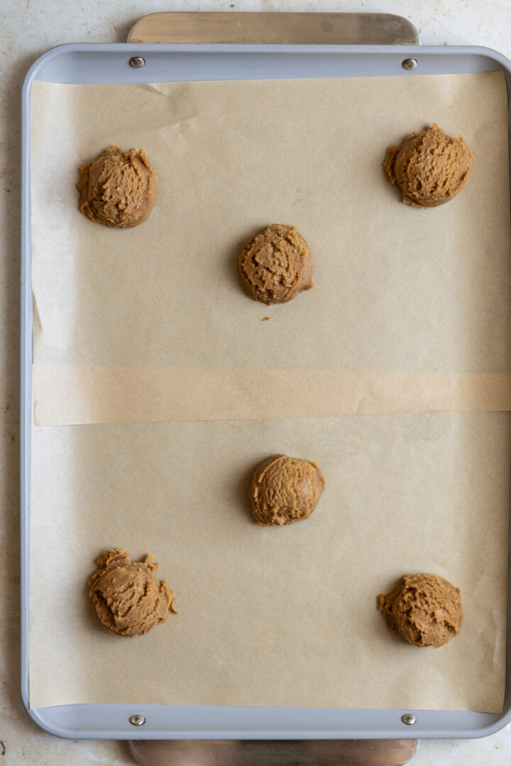 Dough balls on a cookie sheet lined with parchment paper.